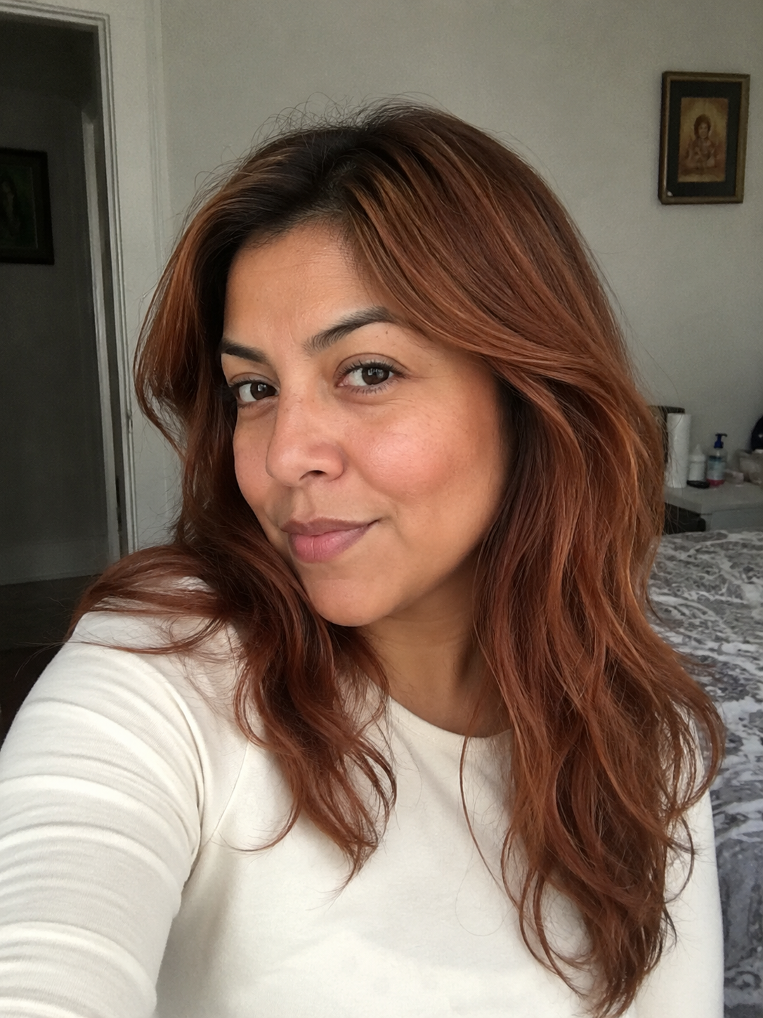 Latina woman with soft copper auburn medium waves and natural brown roots