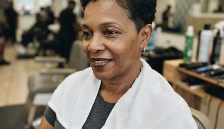 Short curly pixie cut blending gray and black strands with natural texture, ideal for women over 50 embracing gray transitions