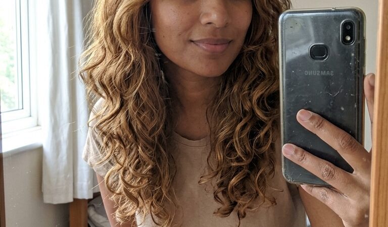 A with long, curly, and color-treated hair featuring a warm, natural-looking Sunset Terracotta Highlights Texture