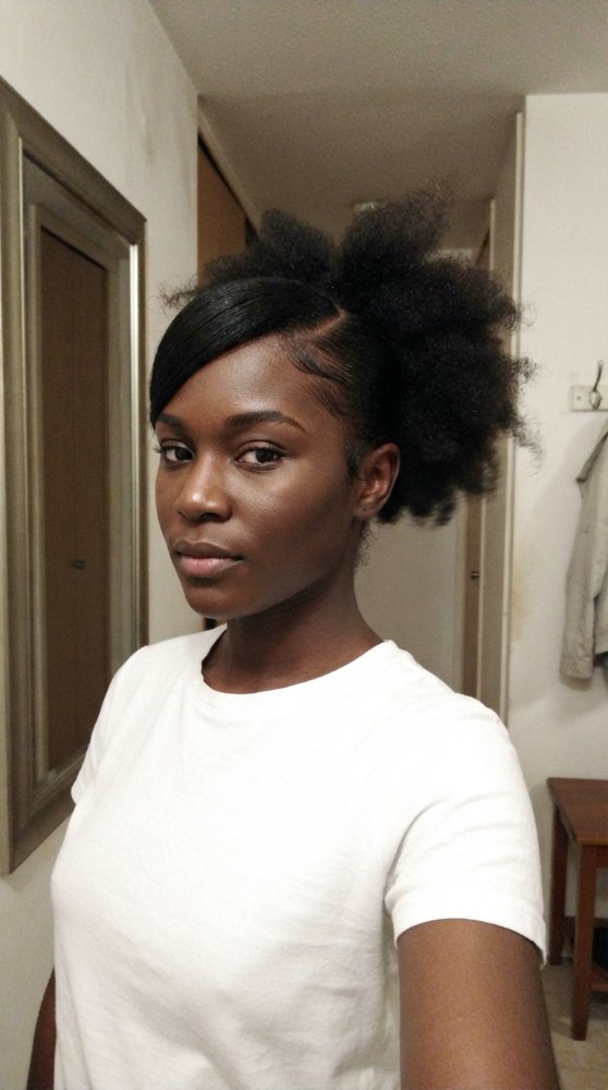 The hair visible in this is black, with the top portion sleek and smooth, while the lower section is puffy and textured. The hair appears to be naturally curly and voluminous, with a clear distinction between the smooth and puffy sections, and there is a defined edge where the sleek section frames the face. The overall style suggests a contrast between the sleek, face-framing section and the fuller, more voluminous top section